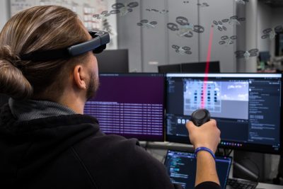 Jan Michalak interacts with a swarm of drones in an augmented reality environment for a scenario focused on status. Photo and illustration by Rodney Kimbangu for Virginia Tech.