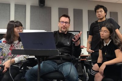 Professor Ico Bukvic is surrounded by three students in the music lab.