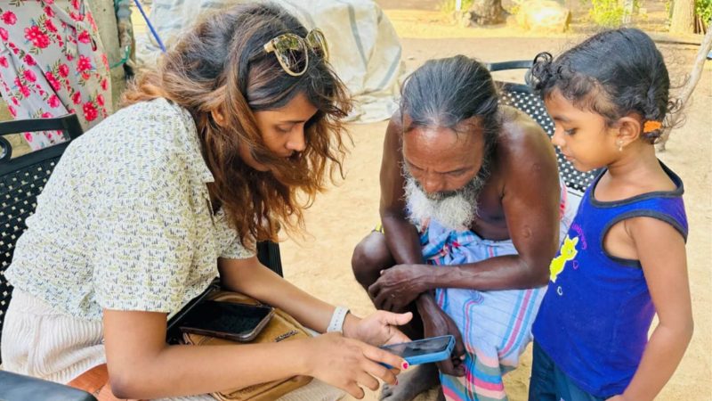 Graduate student Sithuni explains the smartphone to a Coastal Vedda leader.
